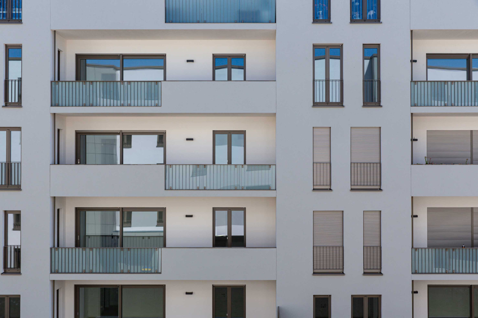 Fassade eines modernen Mehrfamilienhauses mit Balkonen und großen Fenstern